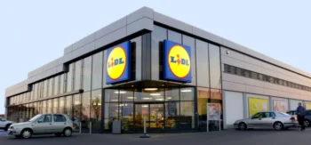 Moderní prodejna Lidl s prosklenou fasádou a výrazným logem na dvou stranách budovy.