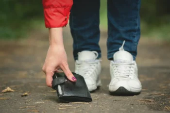 žena zvedající peněženku ze země