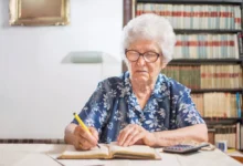 Starší žena zapisující do sešitu financí