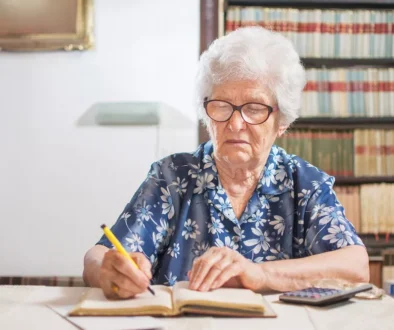 Starší žena zapisující do sešitu financí