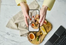 ruce drží telefon a fotí jídlo