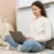 Žena se opírá o topení a pracuje na notebooku