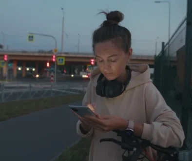 Žena stojí na ulici a kouká do telefonu
