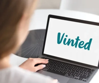 Žena sedící u stolu s otevřeným notebookem, na kterém je zobrazeno logo Vinted