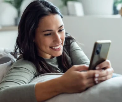 Žena sedí na gauči a drží v ruce mobil