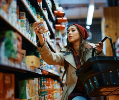 Žena vybírá konzervu z regálu