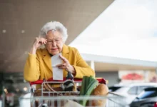Starší dáma čte účtenku cestou z nákupu