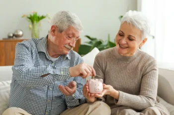 Dva důchodci hází peníze do kasičky