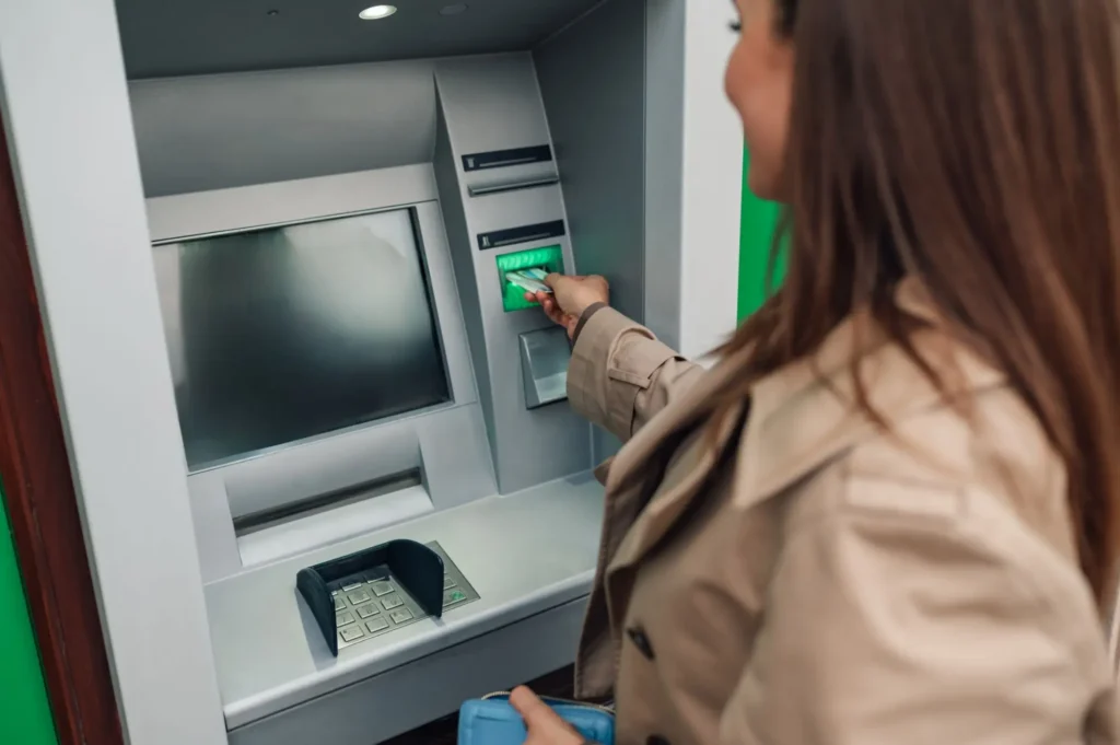 Žena vybírá peníze z bankomatu