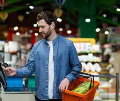 Muž s nákupním košíkem u samoobslužné pokladny